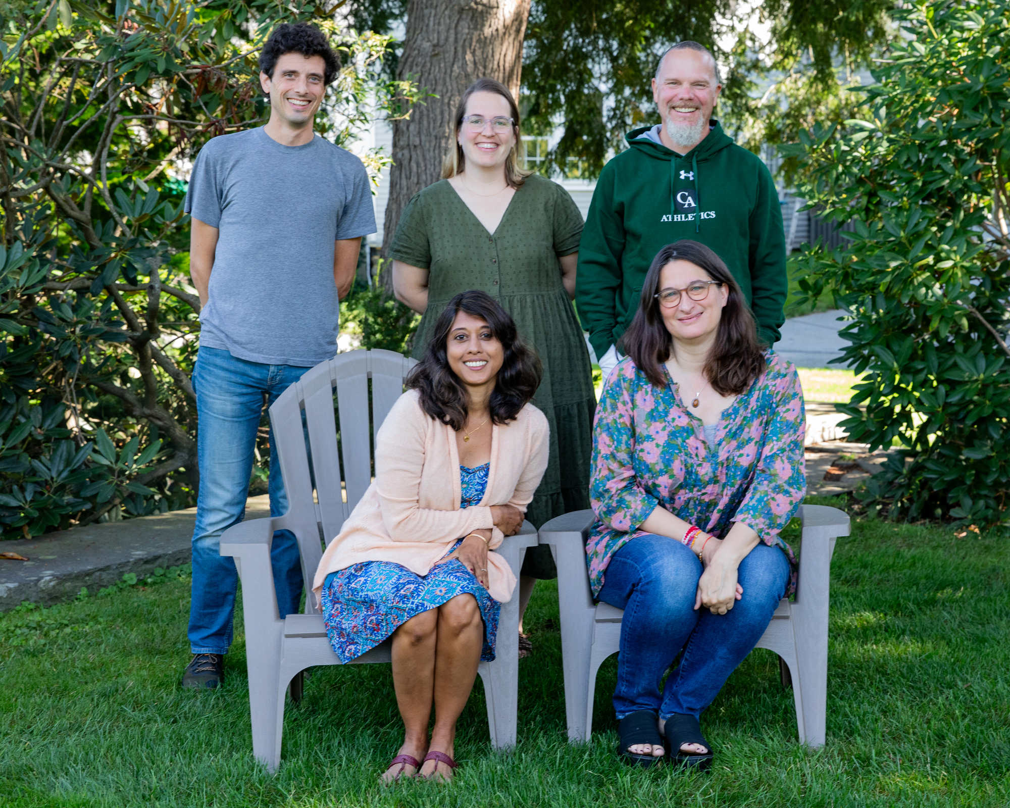 Six faculty and staff members pose for picture on green lawn.