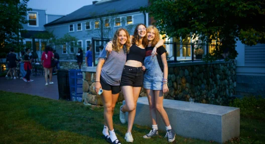 Three girls posing for a photo outside.