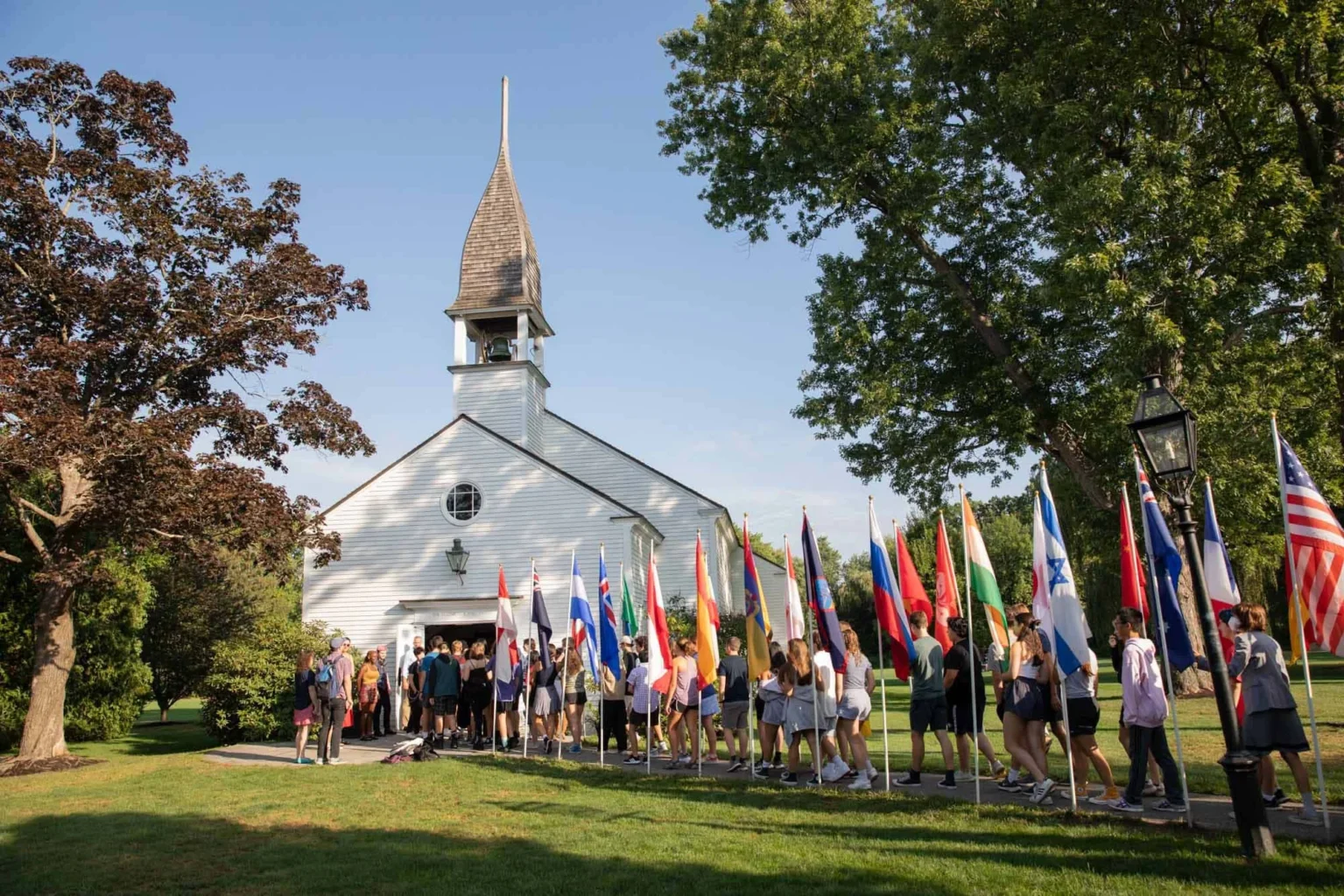Students lined up with various flags in front of a chapel.