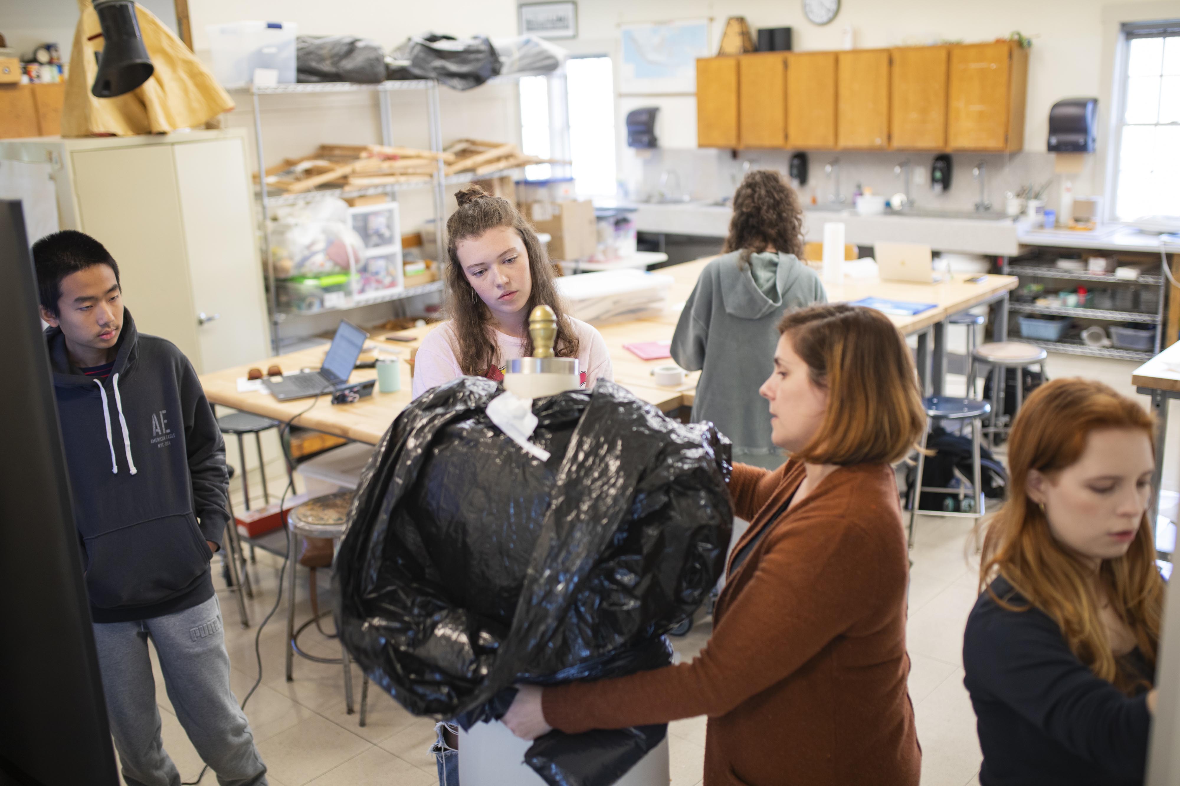 A teacher shows students how to create costume designs in the fiber arts studio.