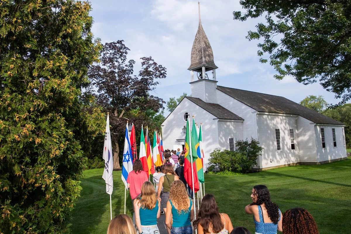 A crowd of people carrying flags walking towards a church