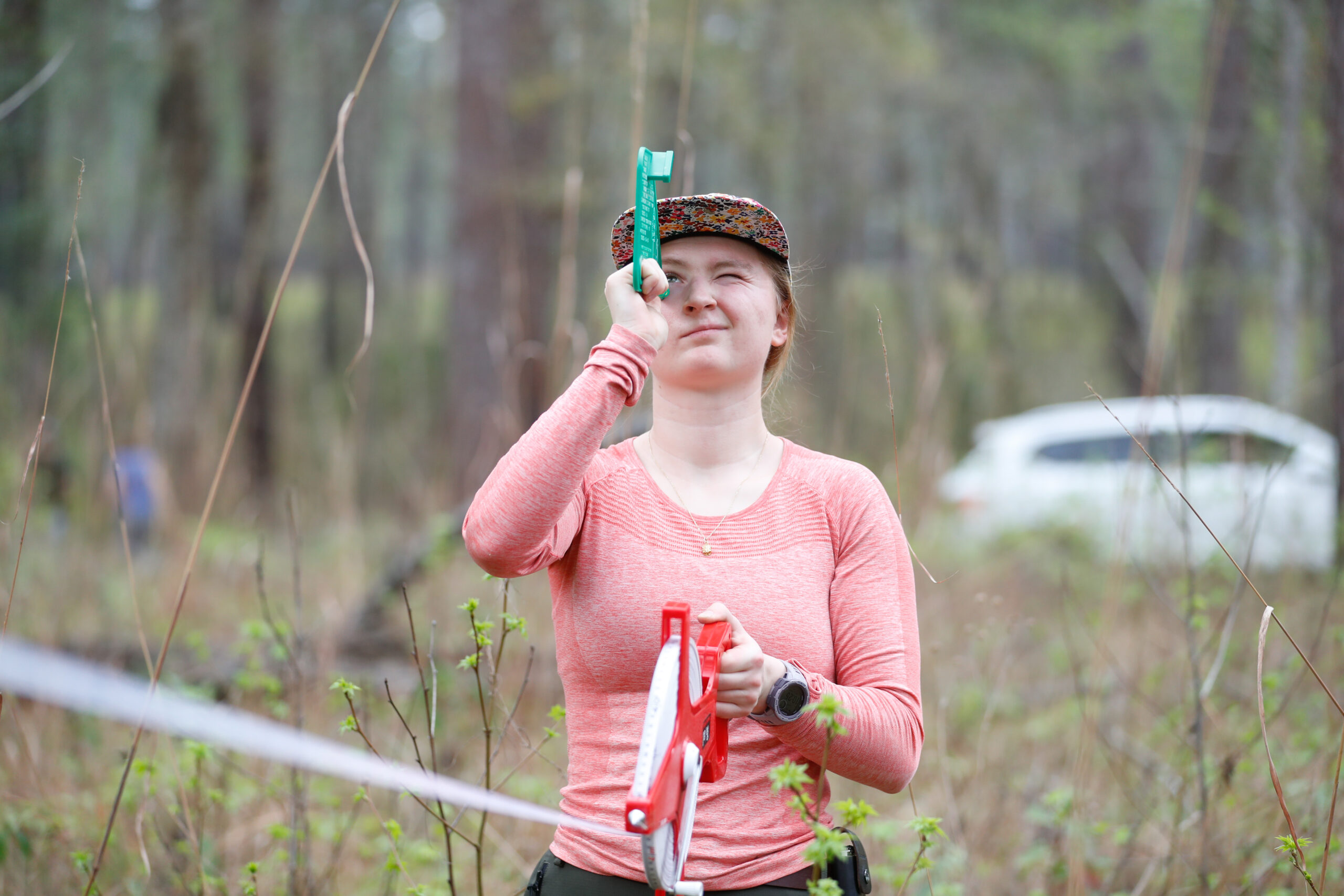 Woman in a pink shirt holding a red and white tape measure