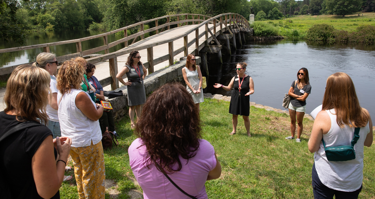 A diverse group of individuals standing by a river, enjoying the scenic view together