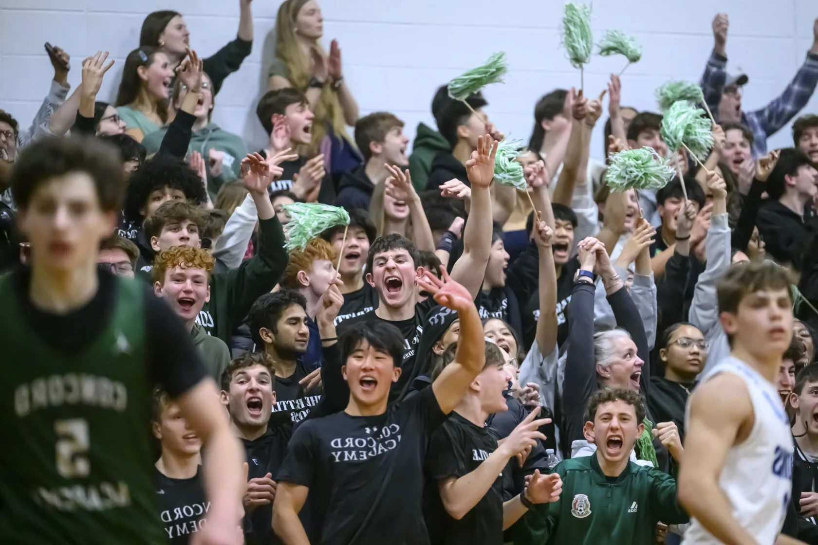 Concord Academy students cheer and wave green pom poms at The Battle.